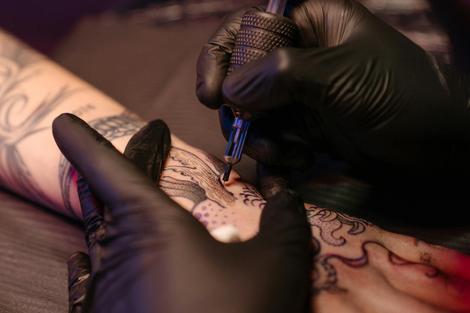 Close-up of a tattoo artist applying ink on a client's arm with precision.